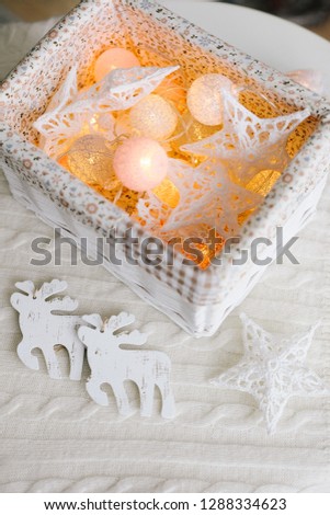 burning Christmas lights are in a beautiful white knit box with wooden white deer