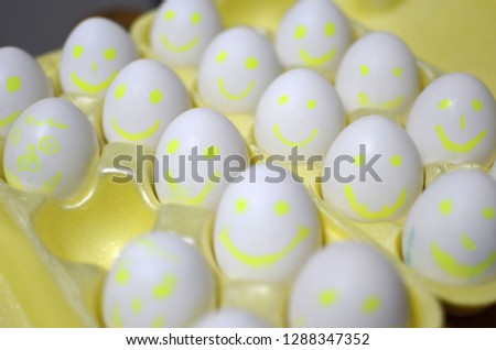 Group of eggs with drawn emotions. White chicken eggs in a cardboard package, with cartoon faces. background, texture