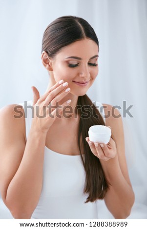 Beauty. Beautiful Woman Applying Face Cream On Soft Facial Skin