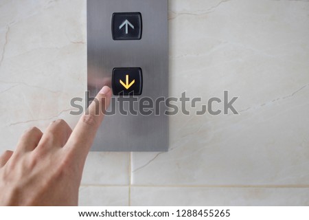 Hand with index finger push the downward elevator button on white color background.