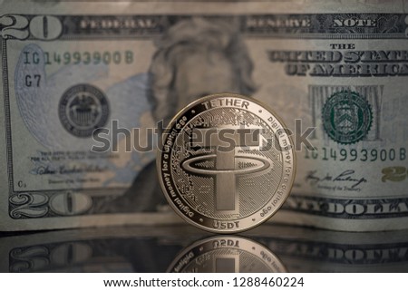 Tether USDT cryptocurrency physical coin placed next to twenty dollars bill on the reflective surface Royalty-Free Stock Photo #1288460224