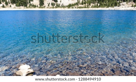Gorgeous view of the shimmering translucent blue green and turquoise jewel tone waters of the glacial Lake Helen in the Lassen Volcanic National Park California