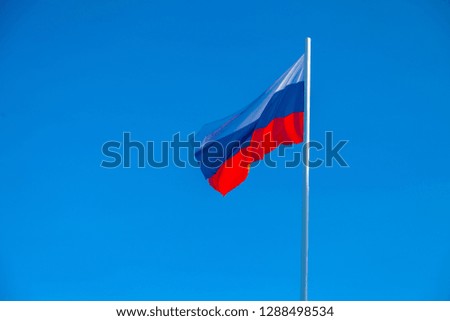 Russian flag fluttering in the wind against a blue sky