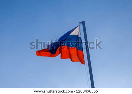Russian flag fluttering in the wind against a blue sky