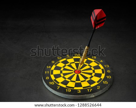 Dart arrow and dart board on black granite board background. Composition with free space for text or design. Top view