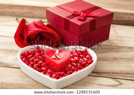 Festive background to the Valentine's day. Flower rose, gift box, a heart-shaped plate and a heart shaped candle. On a wooden background.