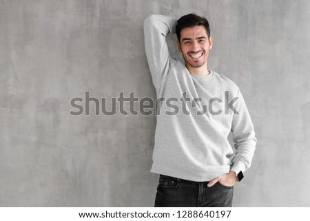 Laughing young man standing against gray textured wall with copy space for your design