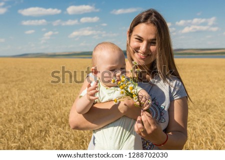 Mother with child in wheat, Young happy family in wheat field smiling and enjoying the sun
