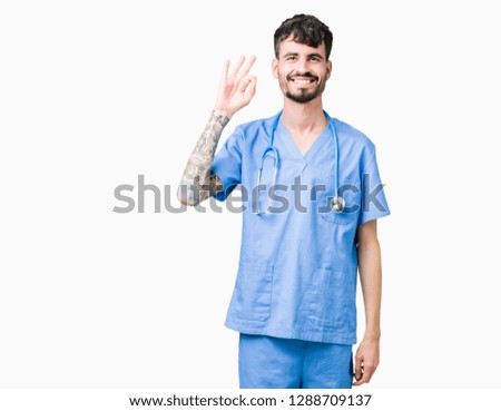 Young handsome nurse man wearing surgeon uniform over isolated background smiling positive doing ok sign with hand and fingers. Successful expression.