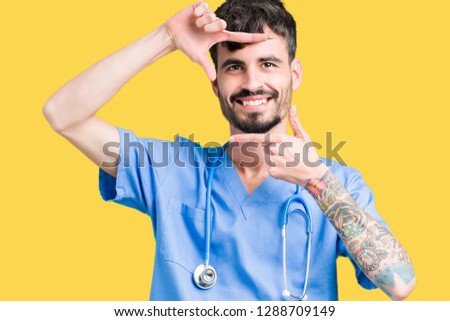 Young handsome nurse man wearing surgeon uniform over isolated background smiling making frame with hands and fingers with happy face. Creativity and photography concept.