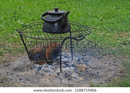 Water kettle on iron grid. extinguished campfire