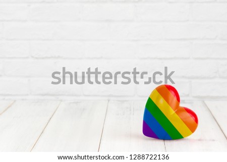 Rainbow heart shaped on white wood background with copy space
