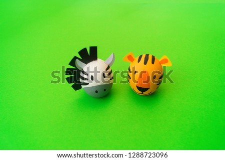 Easter holiday concept with cute handmade eggs: orange tiger and zebra . green background. Festive decoration. Happy Easter