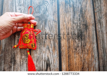 Woman hand holding a Red amulet bag. Chinese alphabet on red bag means good fortune and happiness. Chinese new year festival.