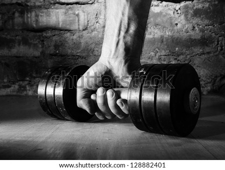 male hand is holding metal barbell against brick wall Royalty-Free Stock Photo #128882401