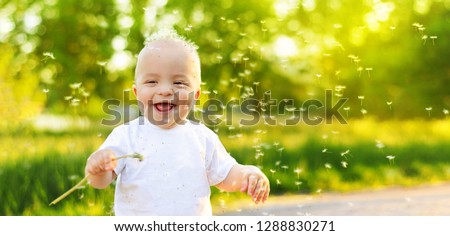 Funny child laughing. Portrait smiling happy baby boy playing spring, summer day,outdoors. Emotion face kid,Close up. Dandelion seeds blowing in wind across natural background park, banner,copy space