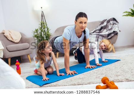 Love to sport. Nice young woman preparing to do push ups while working out with her kids