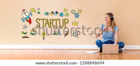 Startup with young woman with headphones using a laptop computer and a pencil