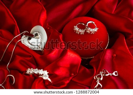 Diamond, women jewelry set;earrings,five and single stone rings,heart shape necklace in the vivid red color satin fabric.Valentine's Day or any special day concept.