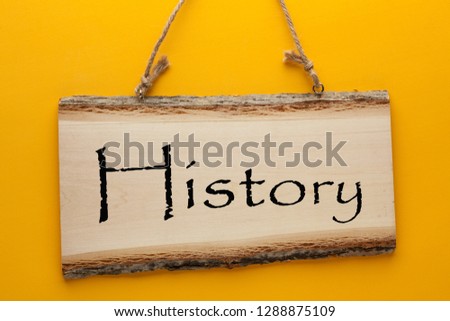 History word on wooden sign hanging on a rope on yellow background. Business concept