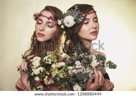 Spring, summer fashion photo shoot at the studio.Two beautiful girls with flowers in the background.Tenderness, beauty on the pictures.Beautiful models.Spring composition of natural flowers.Portrait