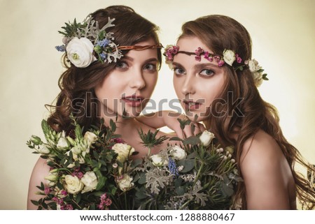 Spring, summer fashion photo shoot at the studio.Two beautiful girls with flowers in the background.Tenderness, beauty on the pictures.Beautiful models.Spring composition of natural flowers.Portrait