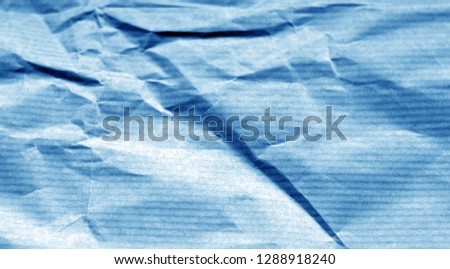 Crumpled sheet of paper with blur effect in navy blue tone. Abstract background and texture for design.