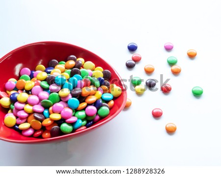 Multicolored chocolate beans in a bowl and side on a white background