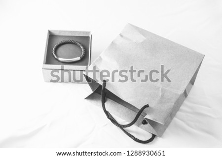 Braided leather men's bracelet with silver insert in the packing box next to the paper bag