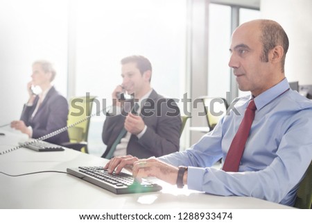 Mature businessman typing on keyboard at desk in modern office