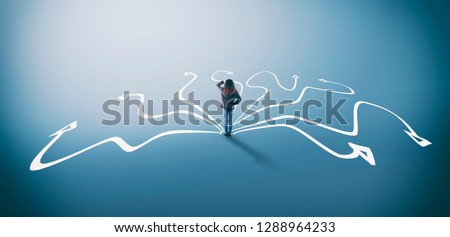 Confused woman stands in front of different arrows . The concept of hard choices. Royalty-Free Stock Photo #1288964233