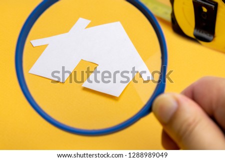 with a magnifying glass on a yellow background and measure in the background. Real estate concept
