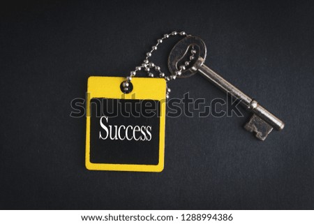 SUCCESS inscription written on wooden tag and key on black background with selective focus and crop fragment. Business and education concept