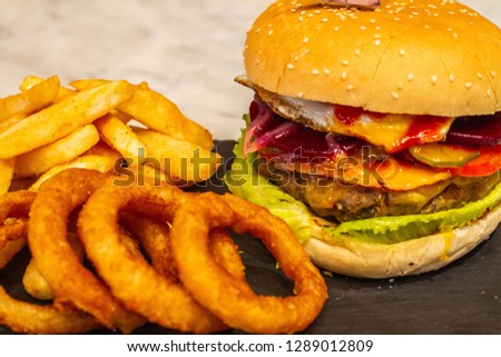 Beef burger with salad eggs tomato sauce chips onion rings 