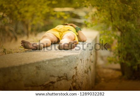 Summer, sunny day. Hippie man sleeping on the parapet among the mountains of Crimea. Picture taken in Ukraine. Horizontal frame. Color image
