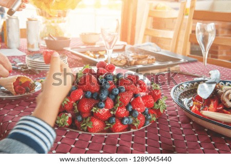 Children's hand takes fruit from a large fruit cake at a children's party.
