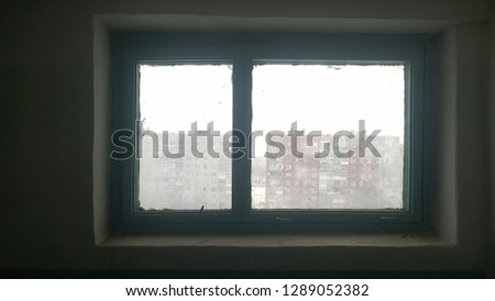 Soiled and defocused image for background. Texture, wallpaper of the old green window showing residential and public buildings and the gray sky of a winter or autumn day.