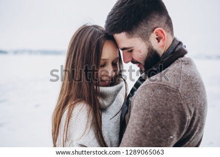 Beautiful young couple have fun, walking, kissing and playing on snow outdoor