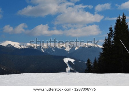 Beautiful view for mountain ridge from the top of skiing slope in winter sunny day. Recreation ski centre in Ukraine. Cloudy sky and snowy background.