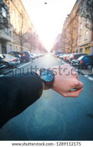 Young businessman wearing watch with coat. Winter in the city. Lifestyle photo. Urban scene in the Prague. 