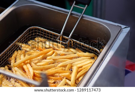 Closeup view of making french fries  deep frying in an equipment in fast or Indian fast food court                              Royalty-Free Stock Photo #1289117473
