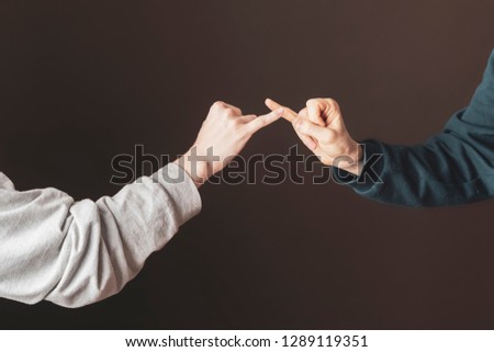 two men hold their little fingers and make peace