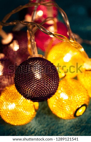 Battery garland with metallic grid balls on blue blanket. Closeup view with blurred background.
