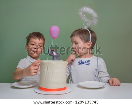 Two boys lick a cake cream. Two boys dressed in white eating birthday pie with hands. Sibligns Day celebration. Newborn sibling party celebration.