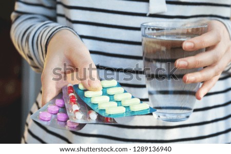 Woman hands holding color pills and a glass of water. Health concept.