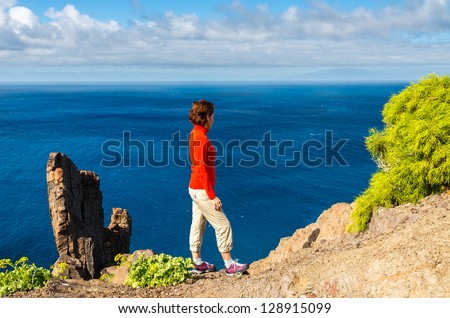Young woman tourist looking ocean view white clouds blue sky, near Alojera village, La Gomera, Canary Islands
