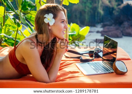 Female european photographer photographing with digital camera on the beach.beautiful woman in coral bikini swimsuit in the tropical paradise sea taking pictures of the landscape photo shoot