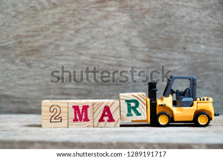 Toy forklift hold block R to complete word 2mar on wood background (Concept for calendar date 2 in month March)
