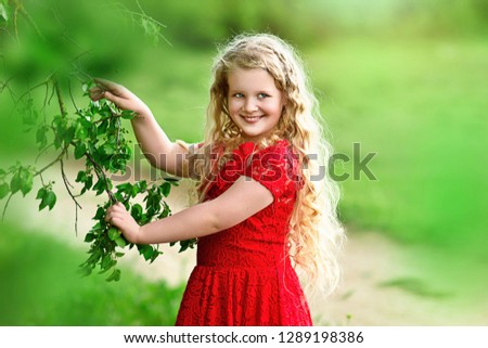 Beautiful blonde little girl with very long hair in green field.