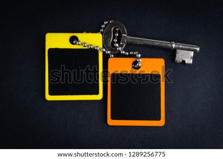 Key and wooden tag on black background with selective focus and crop fragment. Business and copy space concept